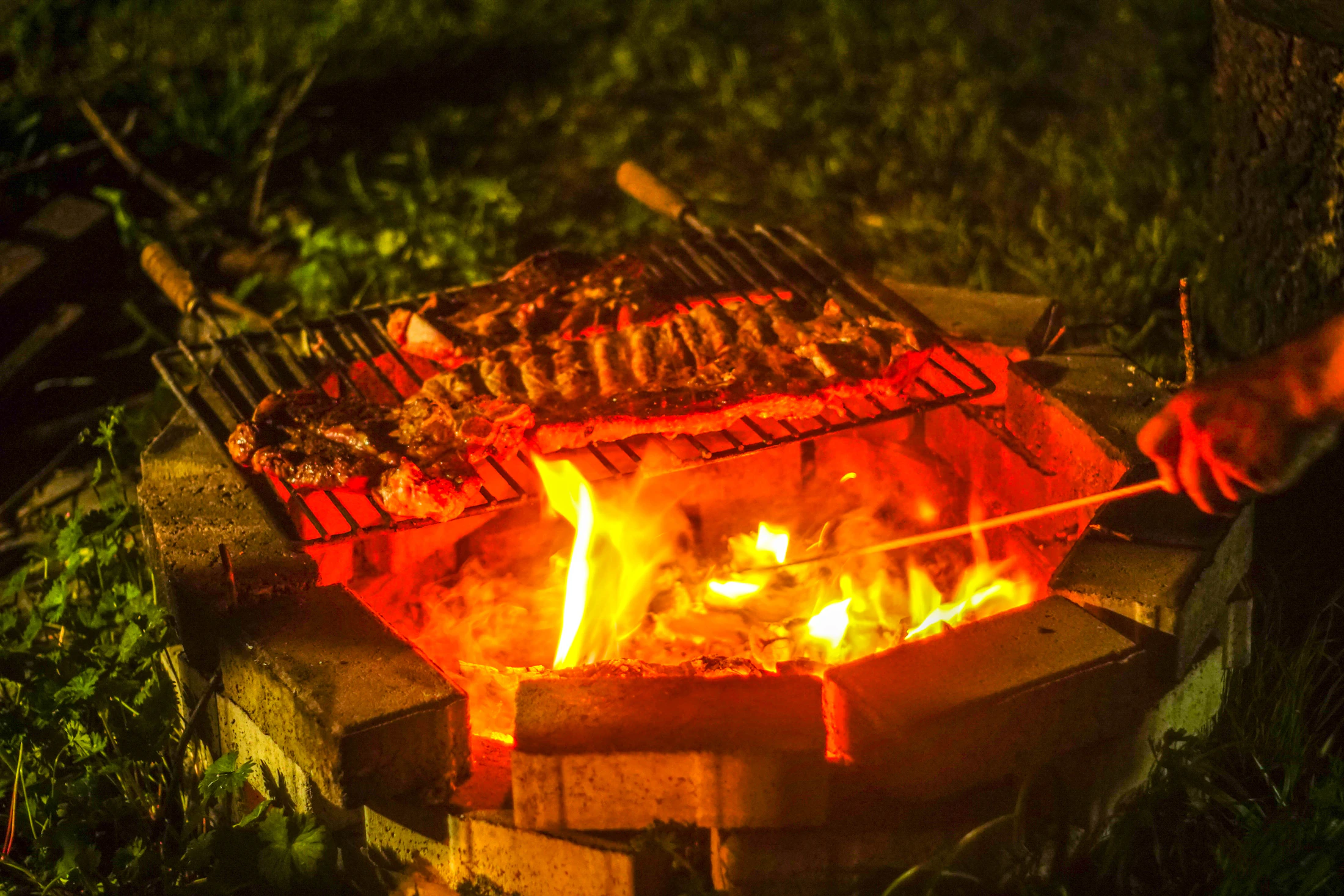 Brasa acesa e carne na grelha, em um churrasco ao ar livre